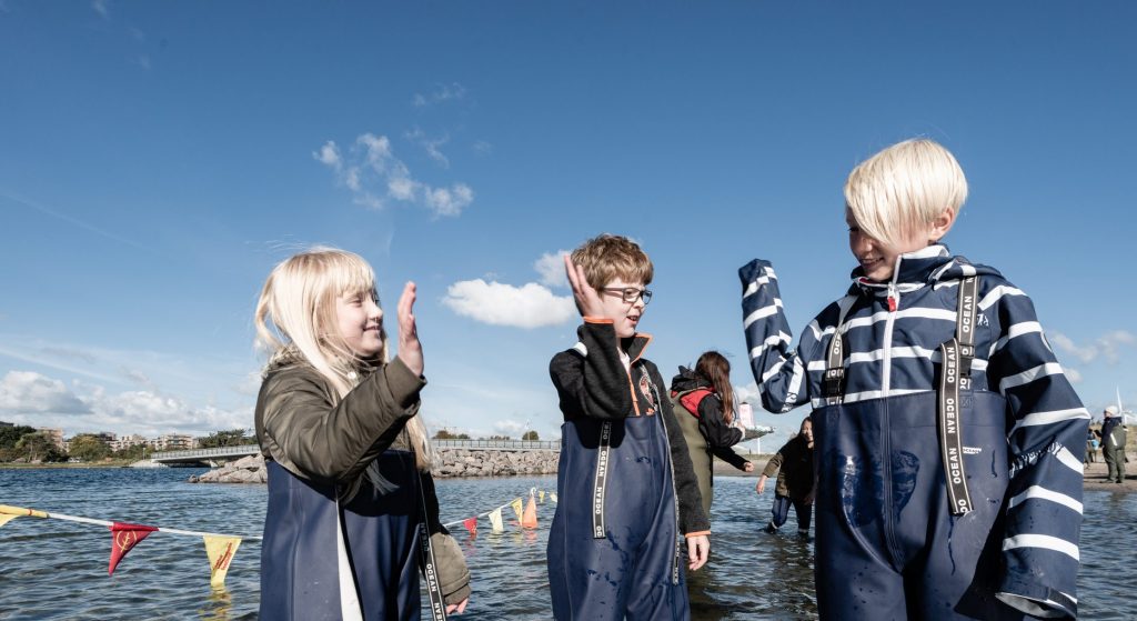 Børn iført waders laver high-five