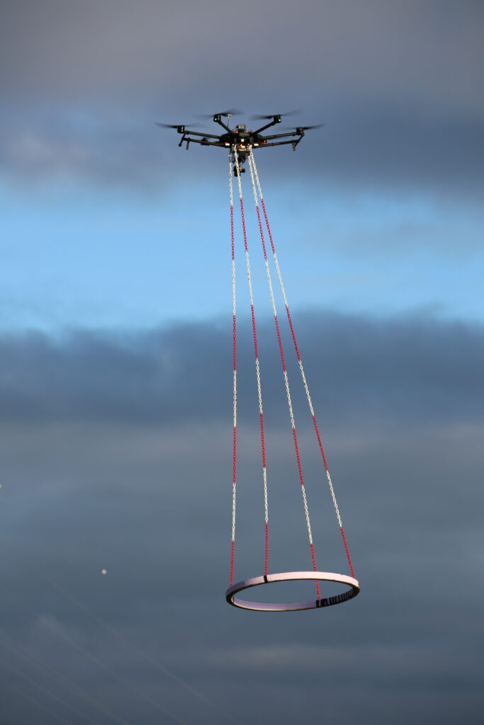 Drone i luften med TEM-teknologi hængende under sig.