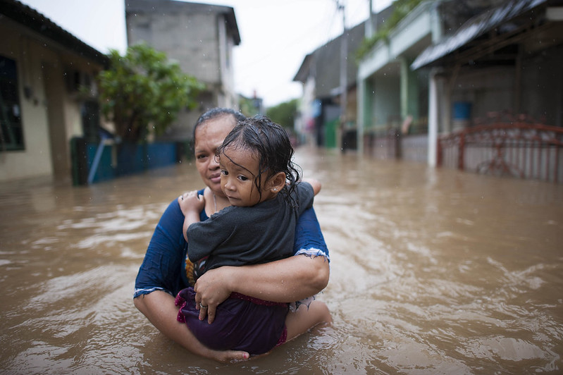 Woman with child walking the flooded streets of Jakarta
