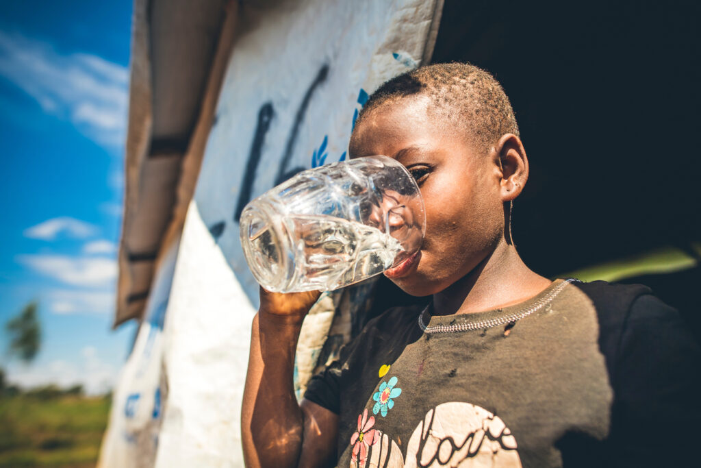 Child in refugee camp drinking water