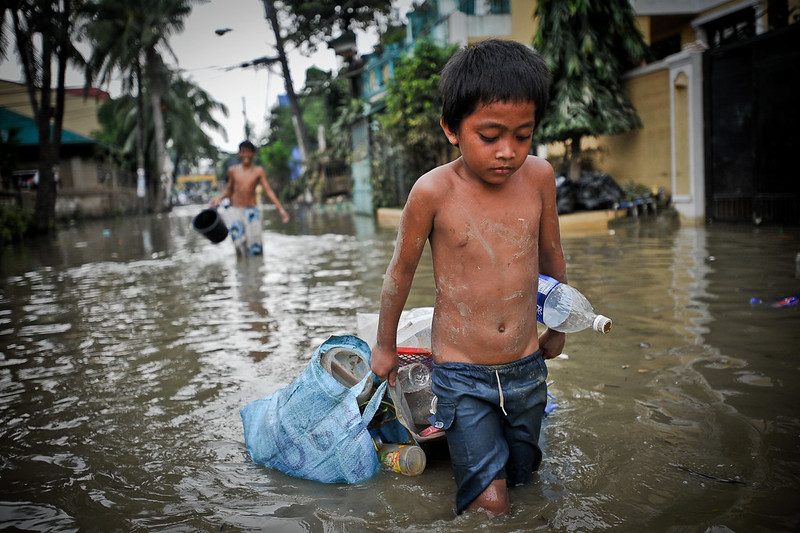 Boy wading through flooded street.