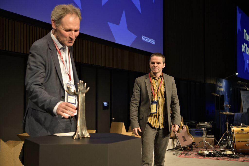Formand Flemming Konradsen overrækker Grundfospris-statuetten til Patrick Biller.
