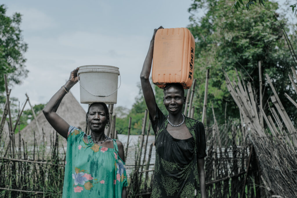 Two women carrying water buckets.