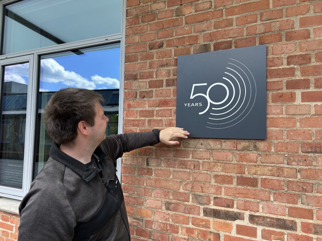Young man fixing a plate to a red brick wall