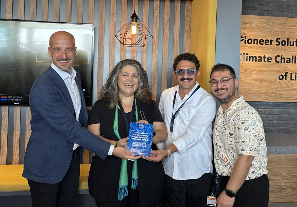 Four people smiling holding a blue statuette